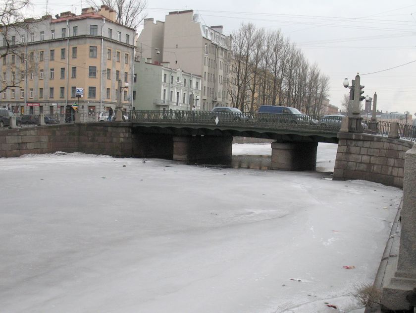 Воды канала Грибоедова скрывает лед. Лишь под Аларчиным мостом видны проталины. Движение машин по мосту.