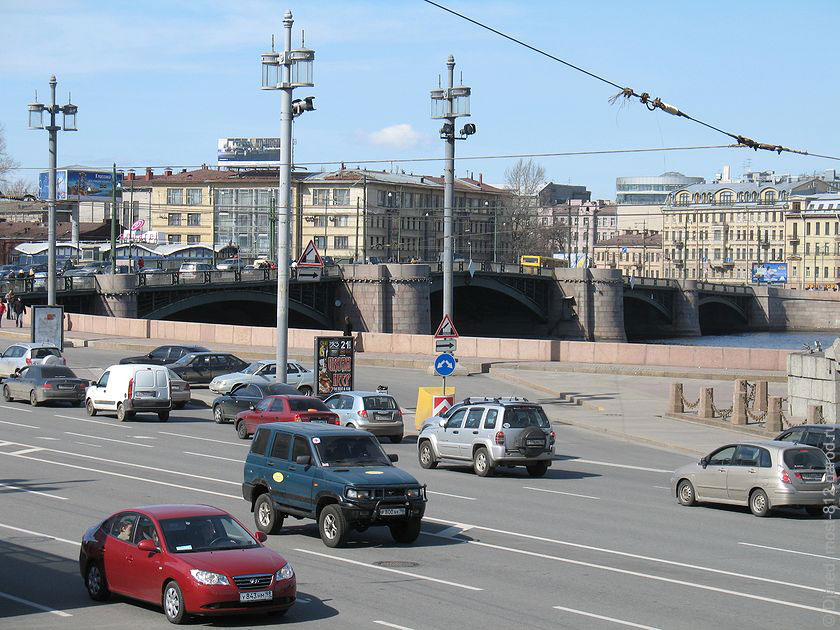 На фото вид на Биржевой мост от здания Биржи, движение машин на Биржевой площади, фонари