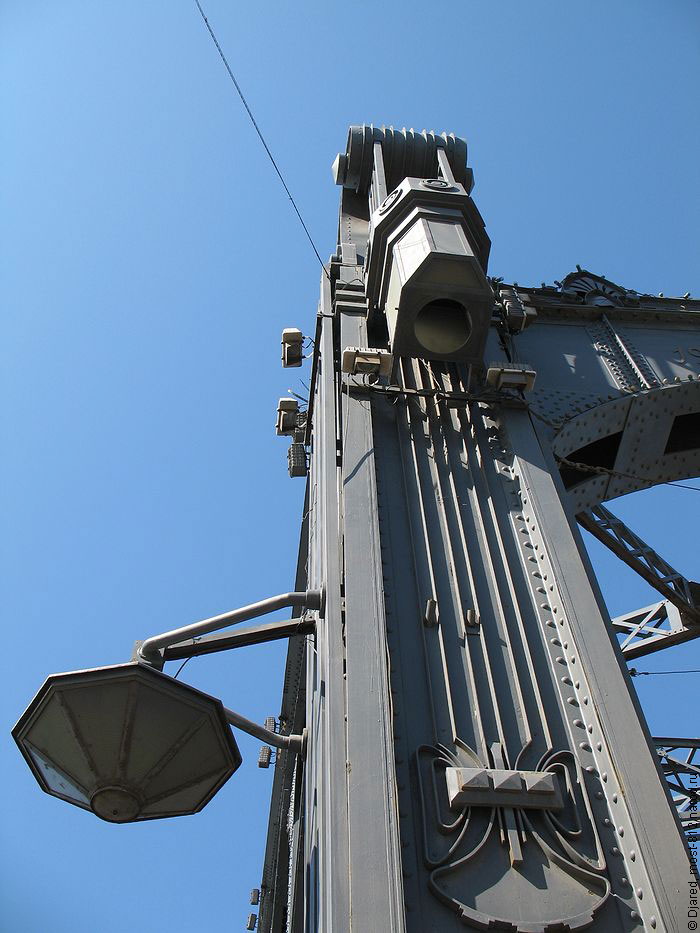 На фотографии изображены фонари на мосту Петра Великого, два фонаря