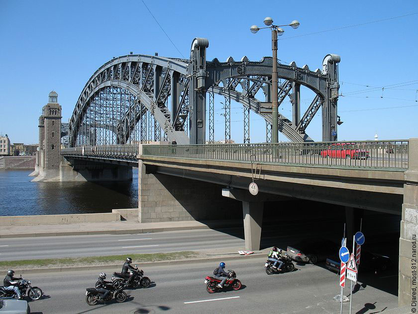 колонна мотоциклистов в шлемах и кожаных куртках под Большеохтинским мостом